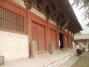The front of a Chinese temple building. It is painted white with ret trim.